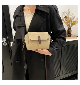 Detail of khaki crossbody bag featuring lychee texture leather and brown buckle