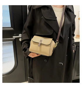 Close-up of beige lychee leather crossbody bag with brown strap and gold hardware