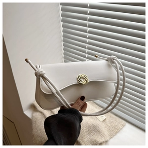 Close-up of white shoulder bag featuring a golden spiral lock and knotted handle detail