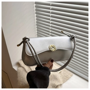 Detail of silver matte flap bag featuring a golden spiral round clasp and knot handle