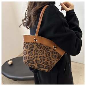 Detail der Tragetasche mit Leopardenmuster und braunem Lederbesatz an einem Model