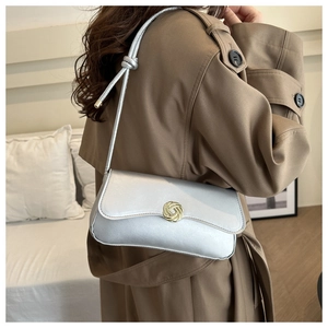 Detail of silver shoulder bag showing gold textured round buckle and knotted strap