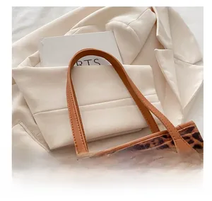 Dettaglio borsa tote leopardata con manico in pelle caramello su blazer bianco