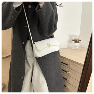 Close-up of white crossbody bag with gold spiral lock on a model in wool coat