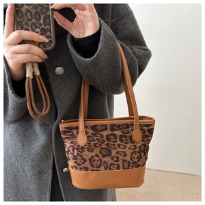 Dettaglio borsa tote con stampa leopardata e manici in pelle marrone su cappotto grigio