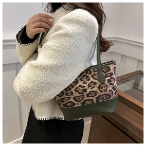 Dettaglio della borsa a secchiello leopardata con tracolla in pelle verde scuro sulla modella