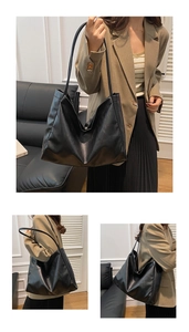 Detailed view of large black tote bag with natural leather texture and long shoulder straps