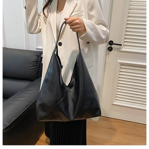 Lifestyle shot of large black faux leather hobo tote bag worn over the shoulder