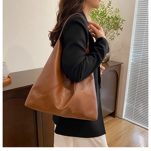 Close-up of caramel brown leather tote bag with soft texture on a model's shoulder
