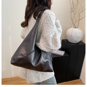 Dark brown large capacity PU leather tote bag shown over the shoulder in a minimalist setting