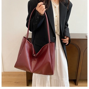 Deep burgundy large tote bag in soft leather shown on shoulder for a chic commute style