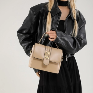 Minimalist khaki leather crossbody bag with round gold buckle on a stylish model