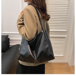 Model wearing a minimalist large capacity black tote bag with smooth faux leather finish