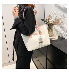 Detail of minimalist cream tote bag with pink handles and cute white plush ball charm