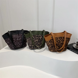 Drei Vintage-Eimertaschen mit Leopardenmuster in Grau, Grün und Braun auf weißem Sockel