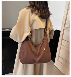 Détail du sac cabas en toile café avec surpiqûres blanches et pompon sur mannequin