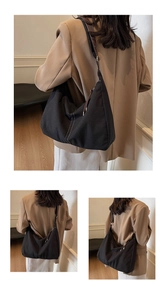 Détail du sac Hobo en toile noire avec coutures blanches et bandoulière en cuir