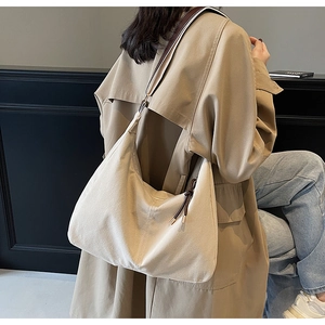 Détail d'un grand sac bandoulière en suédine avec cordons de serrage et sangle rayée