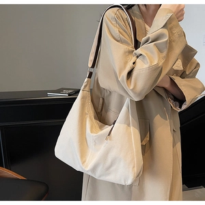 Detail of a beige large-capacity tote bag with brown wide shoulder strap and minimal design
