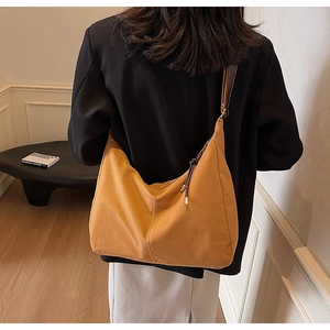 Détail du sac hobo en toile moutarde avec surpiqûres blanches et bandoulière brune