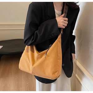 Detail van een mosterdgele suède hobo-tas met lederen riem en decoratieve strikken aan de zijkant