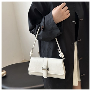 Detail of white crocodile texture crossbody bag with silver H-buckle and knotted strap