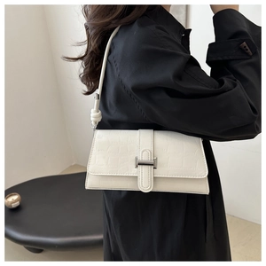 Detail of white crocodile pattern shoulder bag with metal buckle and knot strap detail