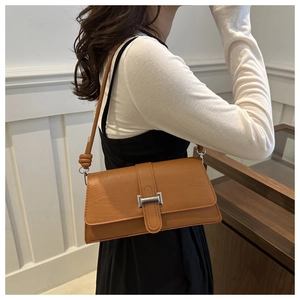 Close-up of brown crocodile pattern leather handbag with knotted strap detail and metal buckle