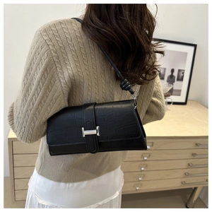 Detailed view of crocodile texture on black shoulder bag with silver metal clasp
