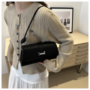 Close-up of black crocodile embossed baguette bag with silver H-shaped metal buckle