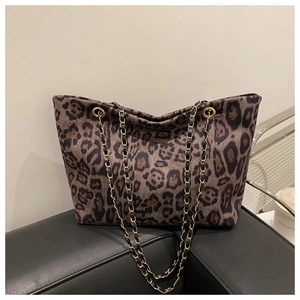 Detail of leopard print tote bag featuring a gold woven chain strap and soft suede texture