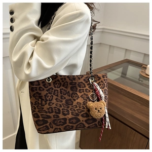 Detail of leopard print tote bag with plush bear charm and metal chain strap