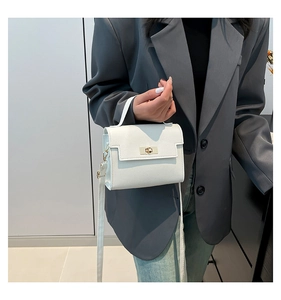 Detailed view of white mini handbag with gold twist lock on a grey blazer outfit