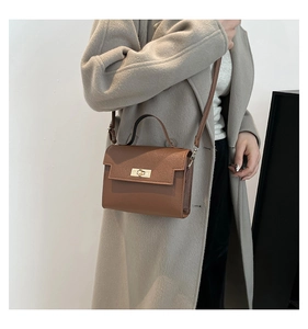 Close-up of caramel leather mini crossbody bag with gold hardware on a grey wool coat