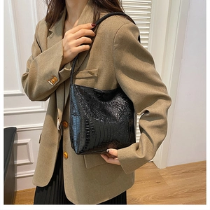 Close-up of black crocodile pattern tote bag shown as a stylish shoulder bag on a model