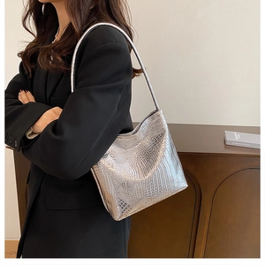 Silver bucket bag with crocodile embossing and metallic luster on a model shoulder