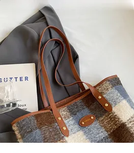 Detailed view of plaid wool tote bag with durable brown leather handles and gold rivets