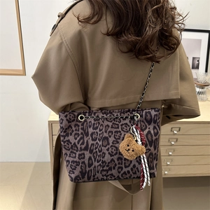 Large leopard print tote bag with metal chain strap and plush bear charm on model