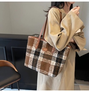 Close-up of checkered wool tote bag with brown leather straps and gold metal logo plaque