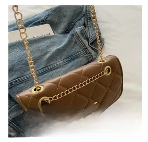 Detail of brown quilted chain bag with gold metal lock and leather texture closeup