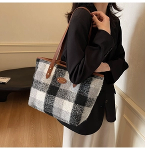 Close-up of winter plaid tote bag with brown leather straps and metal logo detail