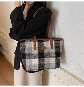 Detail of checkered wool tote bag with brown leather handles and metal rivet reinforcement