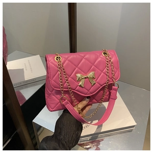 Detail of rose pink quilted crossbody bag with gold bow clasp and metal chain strap