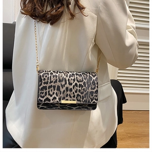 Detail of leopard print crossbody bag with gold chain strap on white blazer