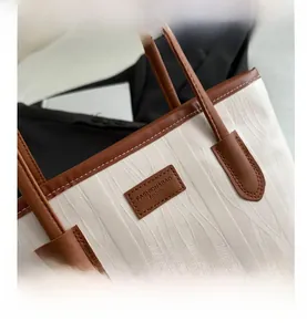 Close-up of woven wave texture and brown leather trim on a large capacity tote bag