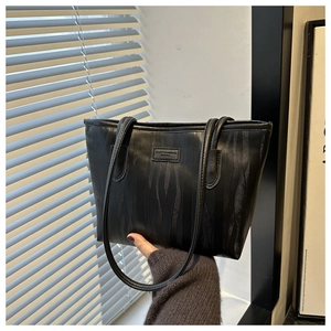 Detail of black tote bag featuring vertical wavy texture and fashion logo plate