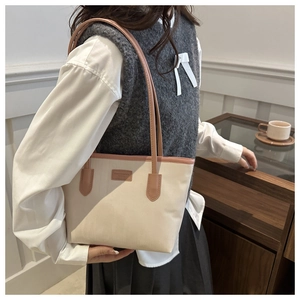 Detailed view of cream-colored tote bag with pink straps worn by a model in soft indoor light