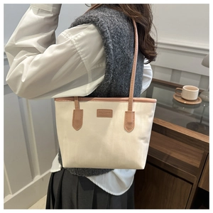Side view of large canvas tote bag with brown leather handles worn by a model