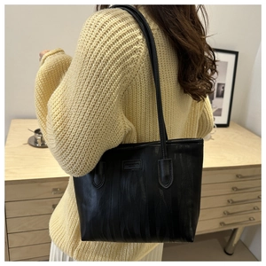 Detail of black tote bag with embossed wavy texture and long shoulder straps