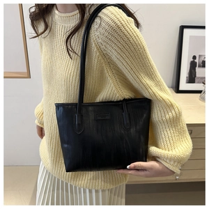 Detail of black PU leather tote bag with vertical texture and Fashion & Bag Design label